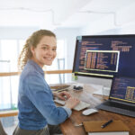 Portrait,Of,Female,It,Developer,Smiling,At,Camera,While,Typing